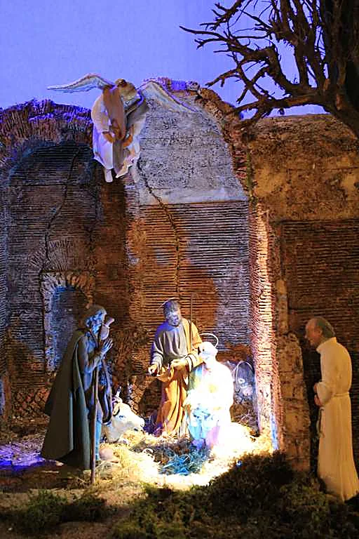 Presepe in stile romano con natività illuminata tra rovine antiche, di notte